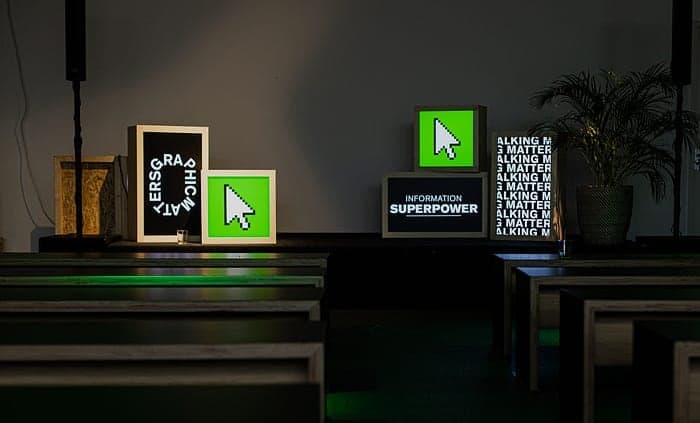 Venue signage at the festival: pixel-cursor lightboxes and an "Information Superpower" display.