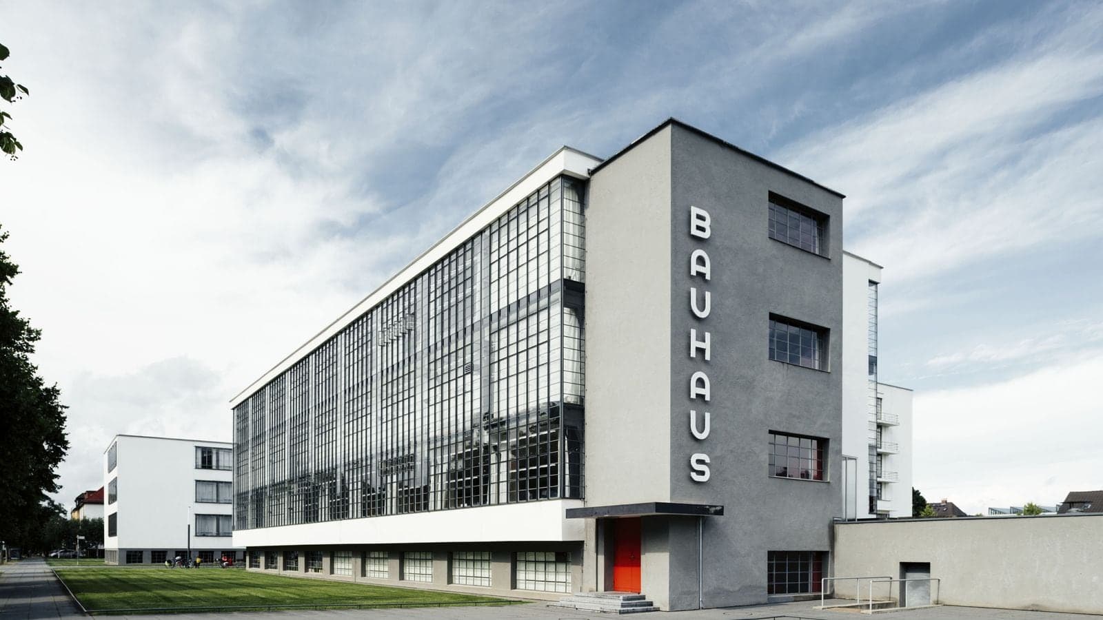 The Bauhaus school building in Dessau, its vertical facade lettering visible against a blue sky.