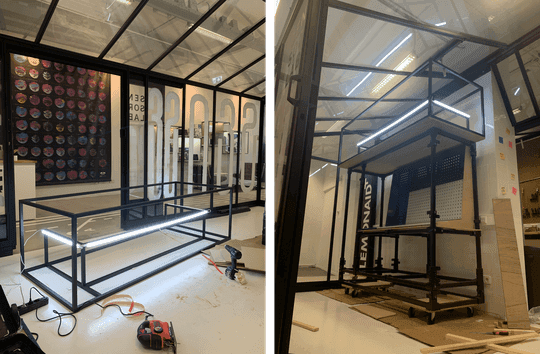 The steel frame under construction in the workshop, LED tubes and power tools visible.